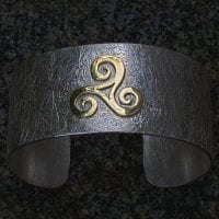 goldene Triscele auf Silberarmspange