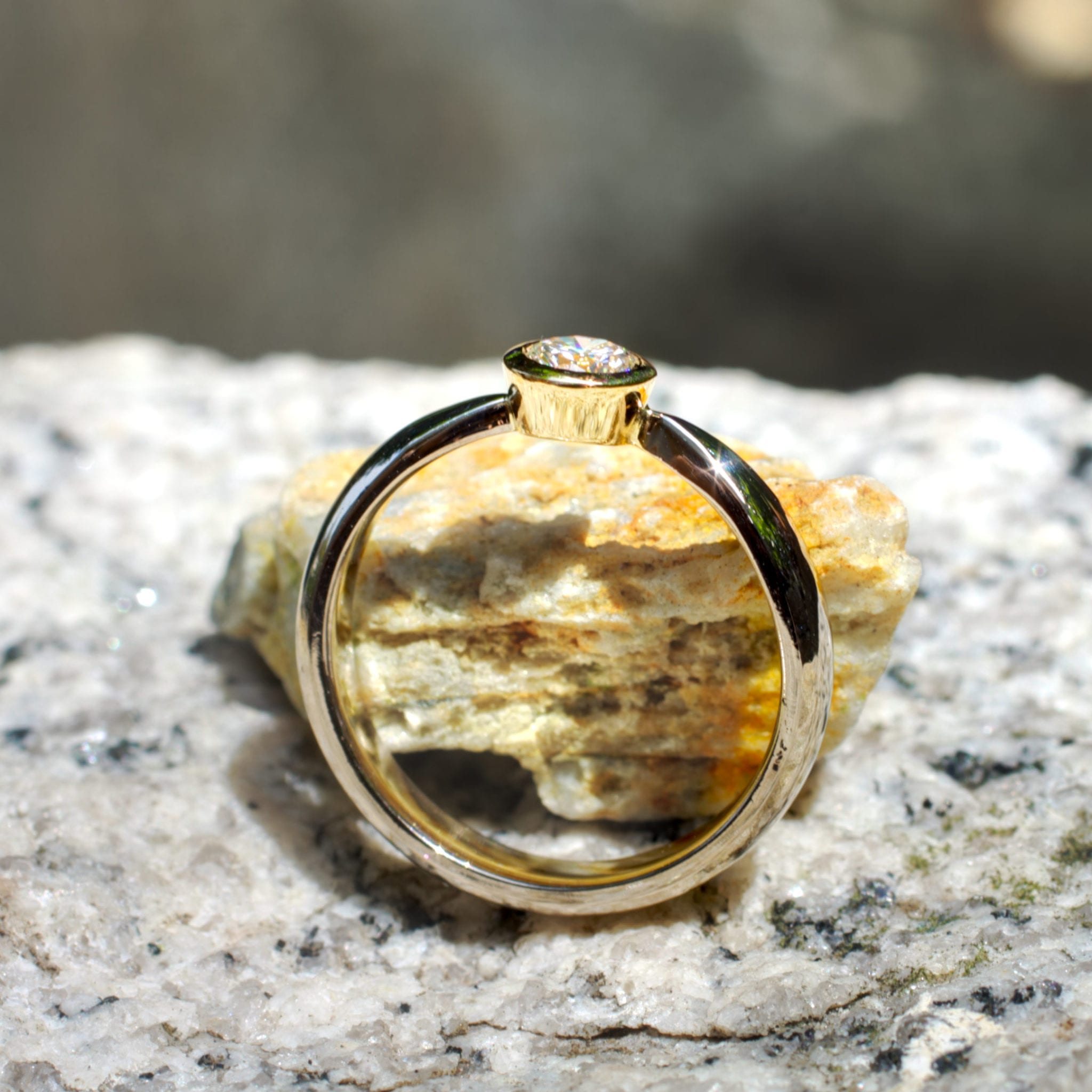 Brillant in konischer Gelbgold-Fassung in zur Fassung spitz zulaufender Weißgoldschiene