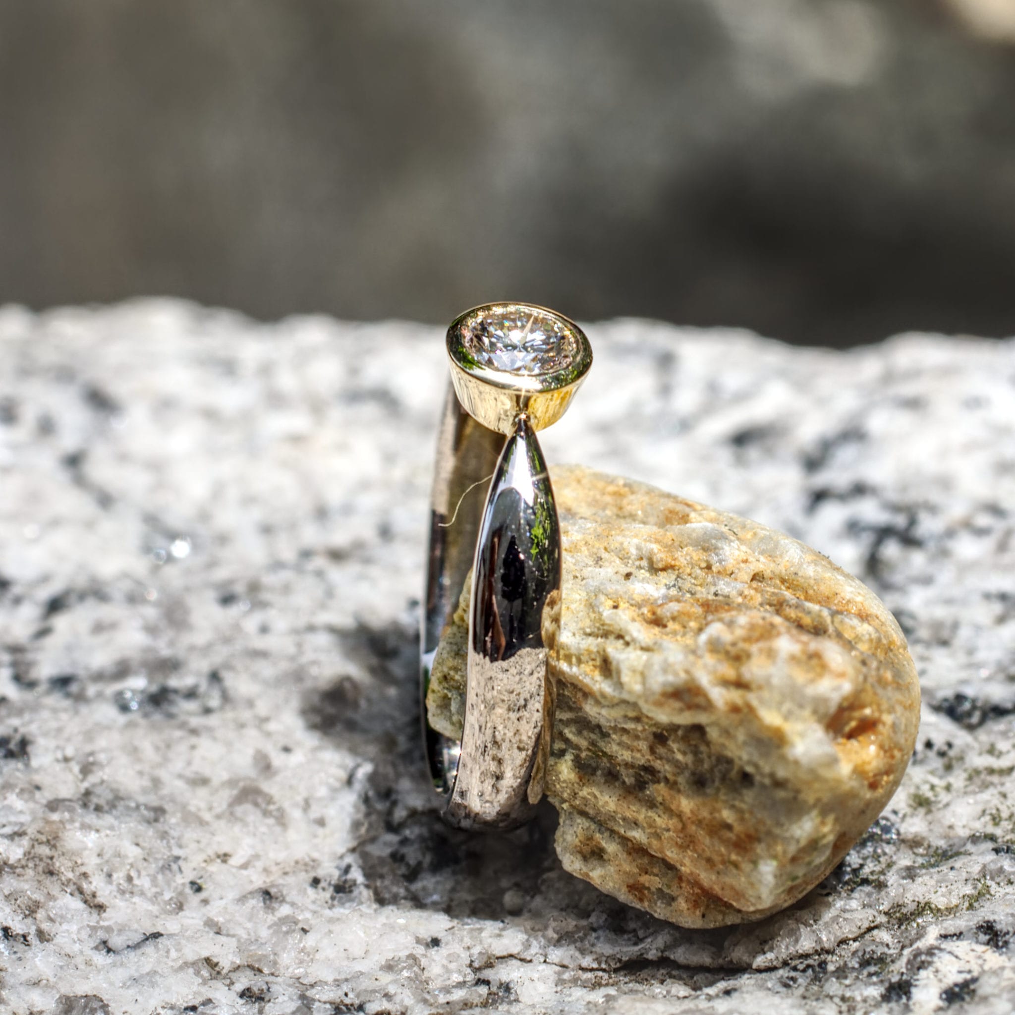 Brillant in konischer Gelbgold-Fassung in zur Fassung spitz zulaufender Weißgoldschiene