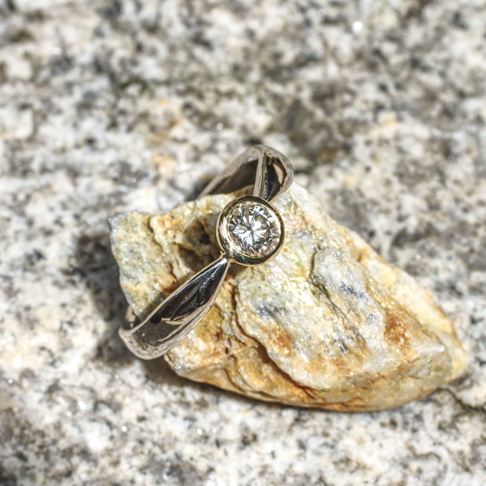 Brillant in konischer Gelbgold-Fassung in zur Fassung spitz zulaufender Weißgoldschiene