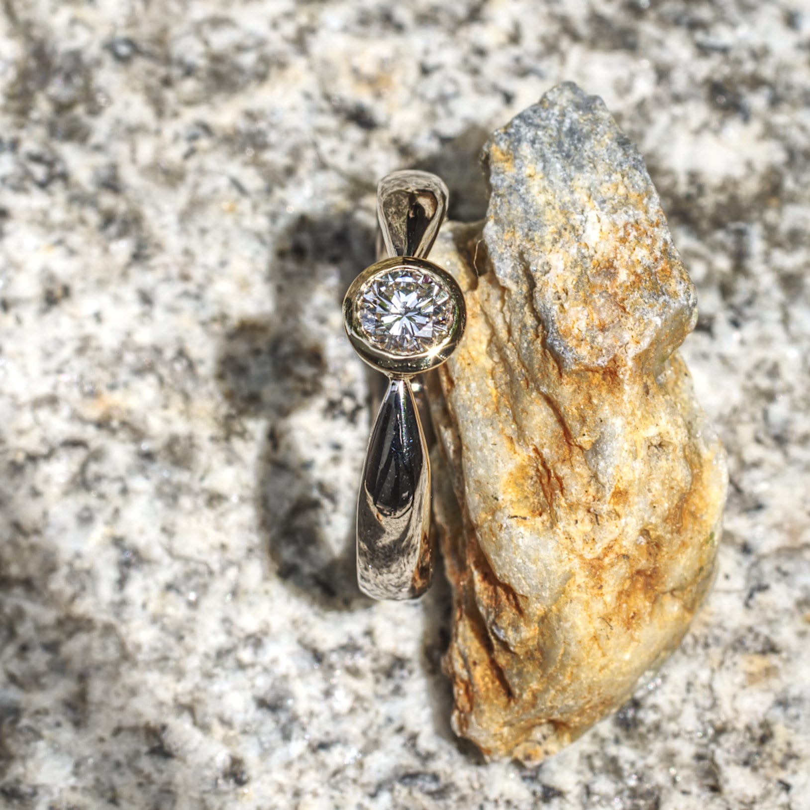 Brillant in konischer Gelbgold-Fassung in zur Fassung spitz zulaufender Weißgoldschiene