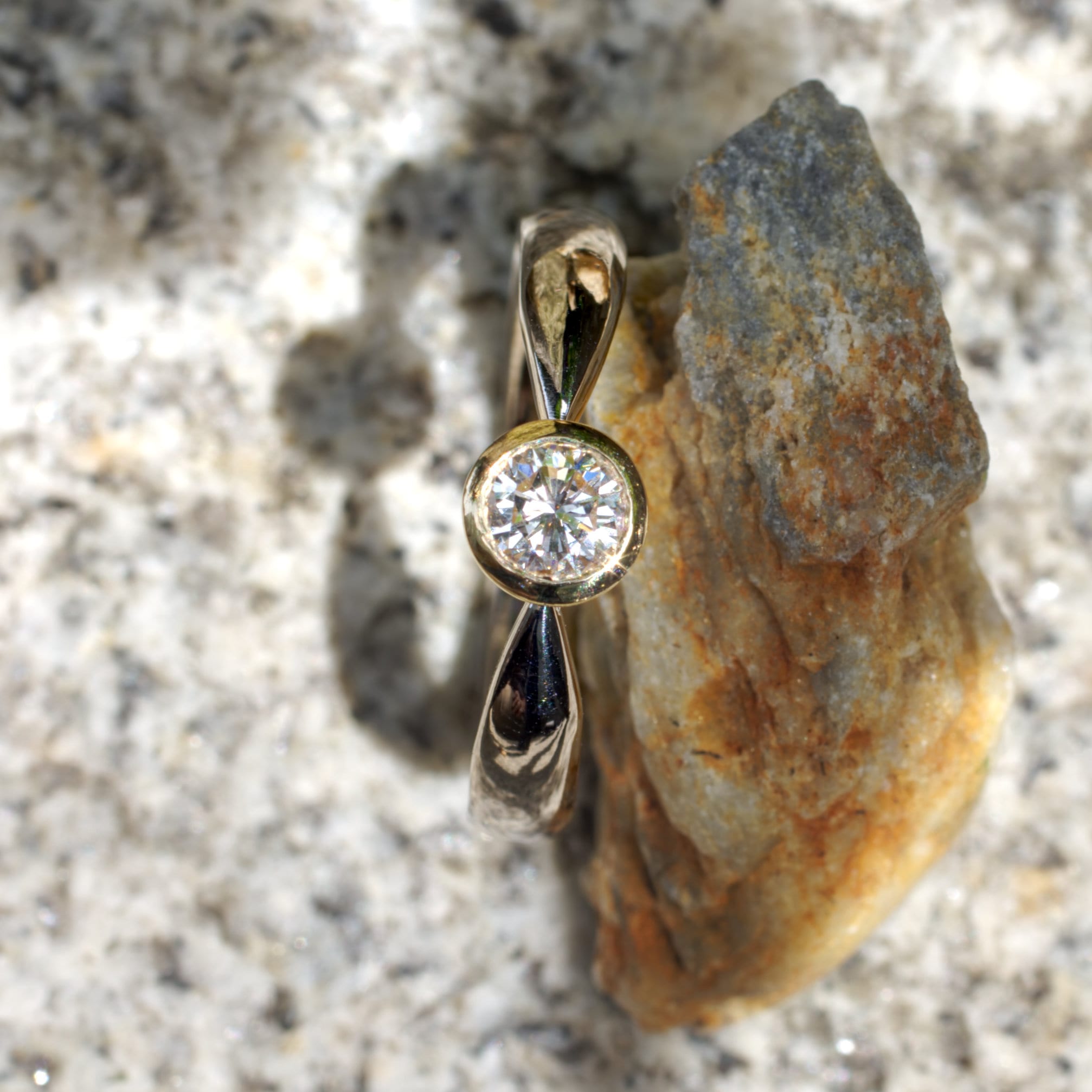 Brillant in konischer Gelbgold-Fassung in zur Fassung spitz zulaufender Weißgoldschiene