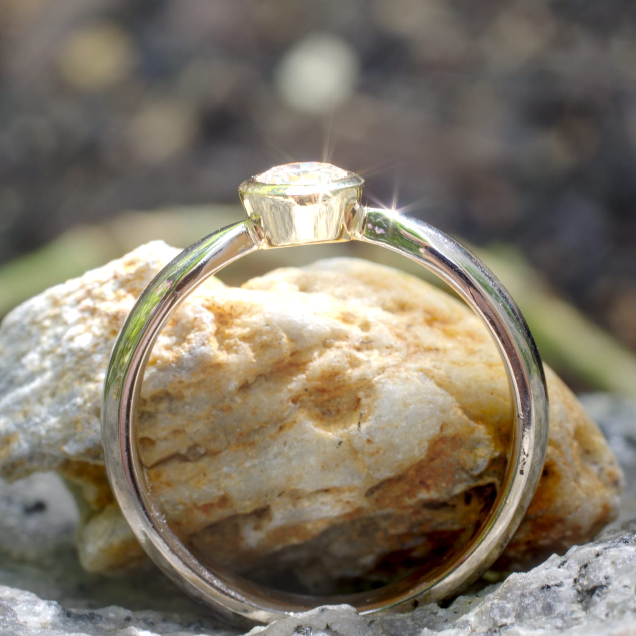 Brillant in konischer Gelbgold-Fassung in zur Fassung spitz zulaufender Weißgoldschiene