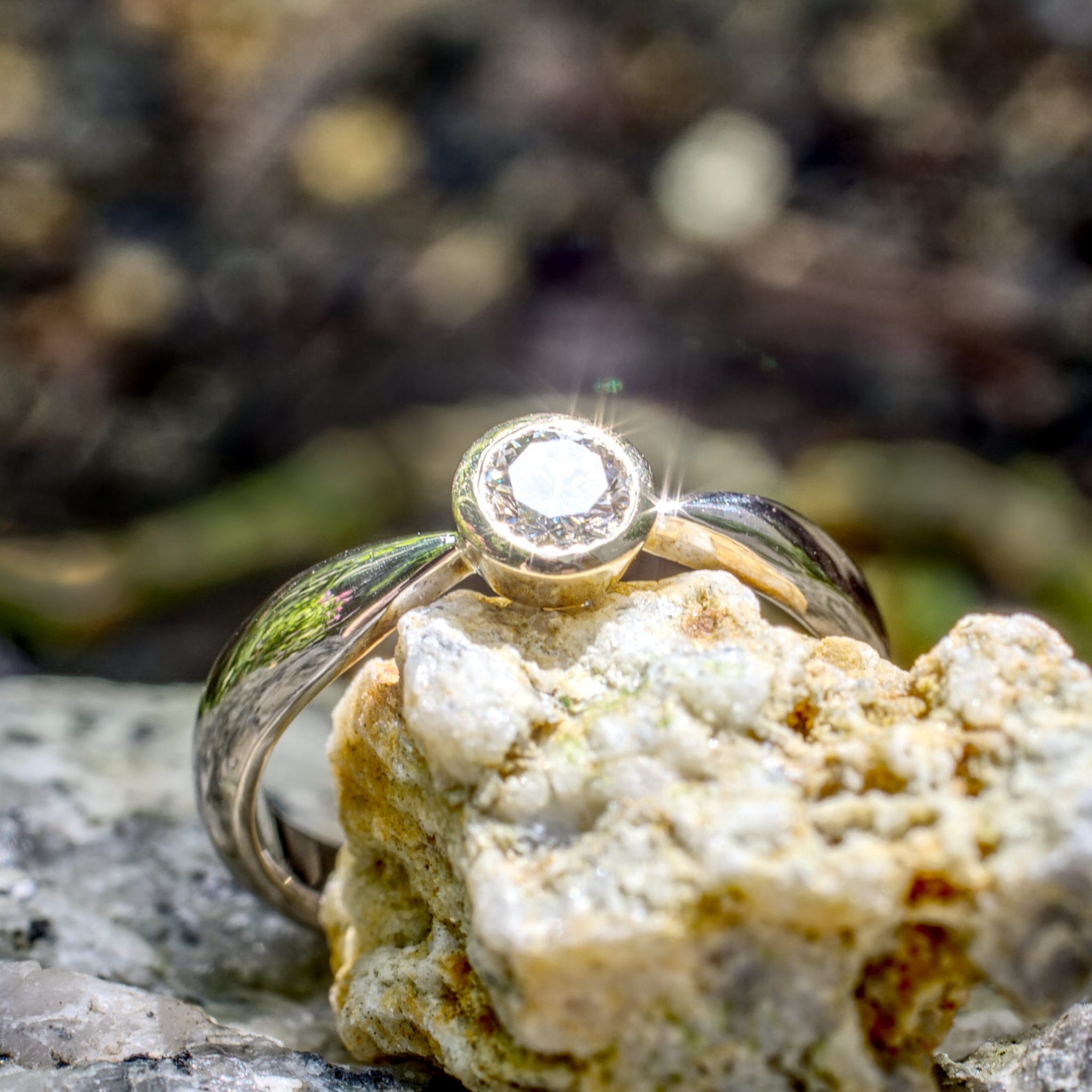 Brillant in konischer Gelbgold-Fassung in zur Fassung spitz zulaufender Weißgoldschiene