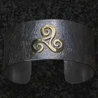 goldene Triscele auf Silberarmspange