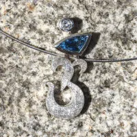 Anhänger in Form eines Om-Zeichens aus Silber mit zwei Steinen