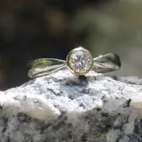 Brillant in konischer Gelbgold-Fassung in zur Fassung spitz zulaufender Weißgoldschiene