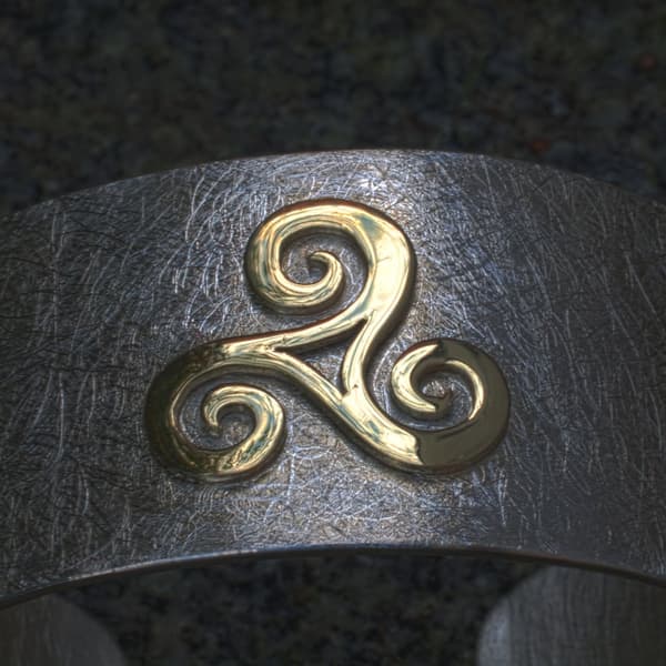 goldene Triscele auf Silberarmspange
